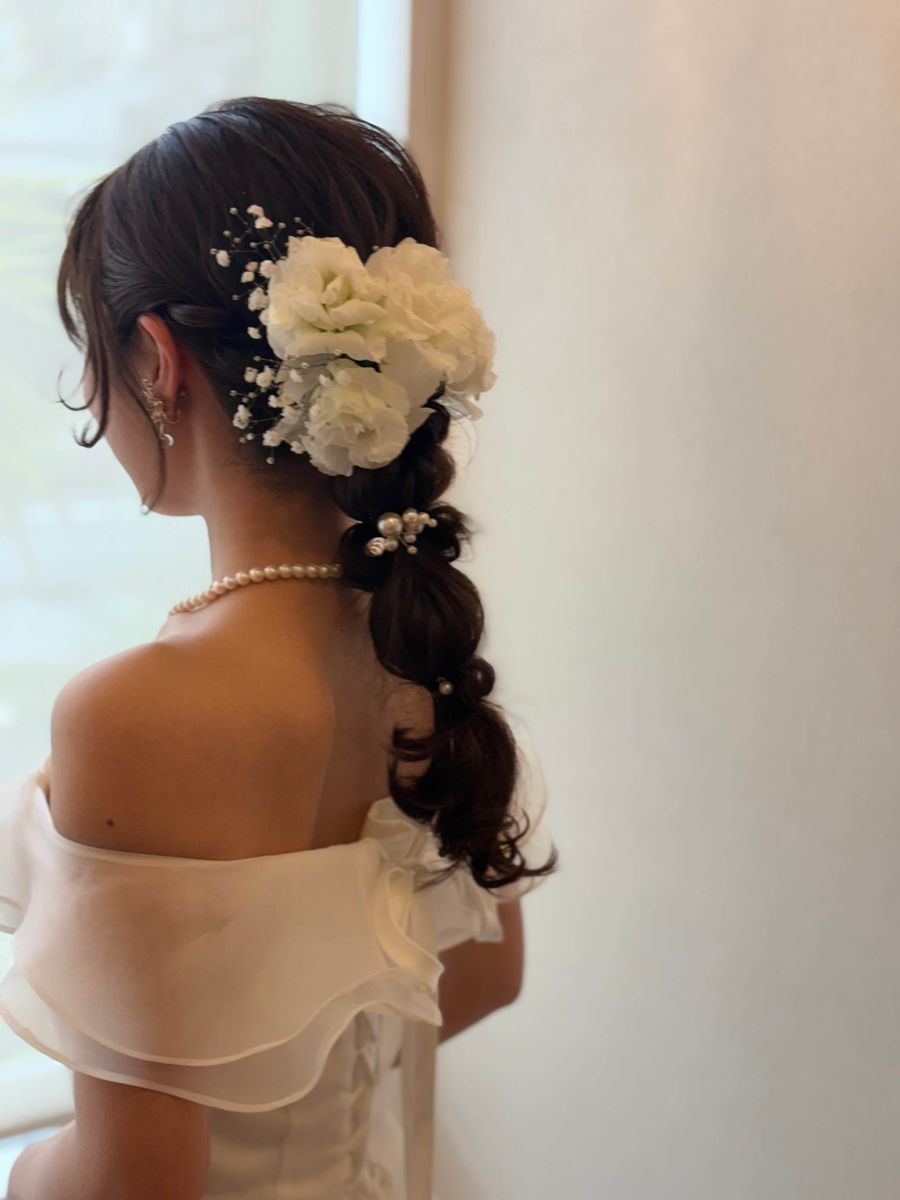 白い生花とパールを飾った編みおろしのブライダルヘア